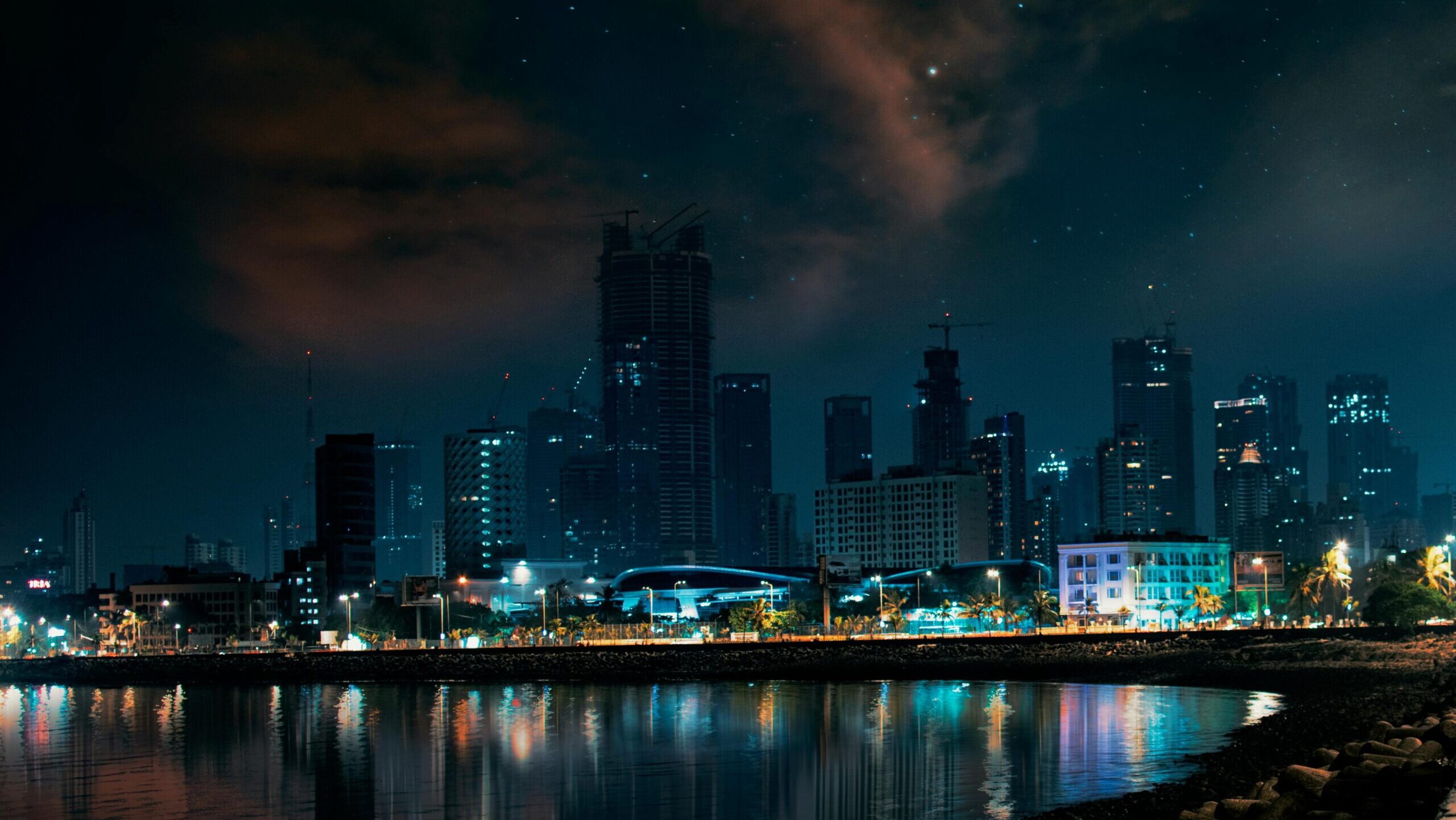 Stunning view of Mumbai's skyline at night, reflecting on water.